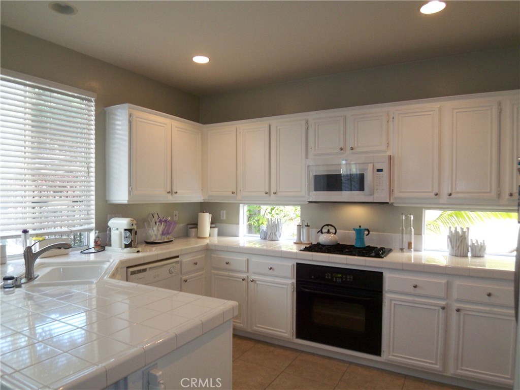 Pristine tile counters and white cabinets make the kitchen welcoming and bright - a wonderful place to prepare a meal fo - 107 Colony Way, Aliso Viejo CA 92656 - photo 1