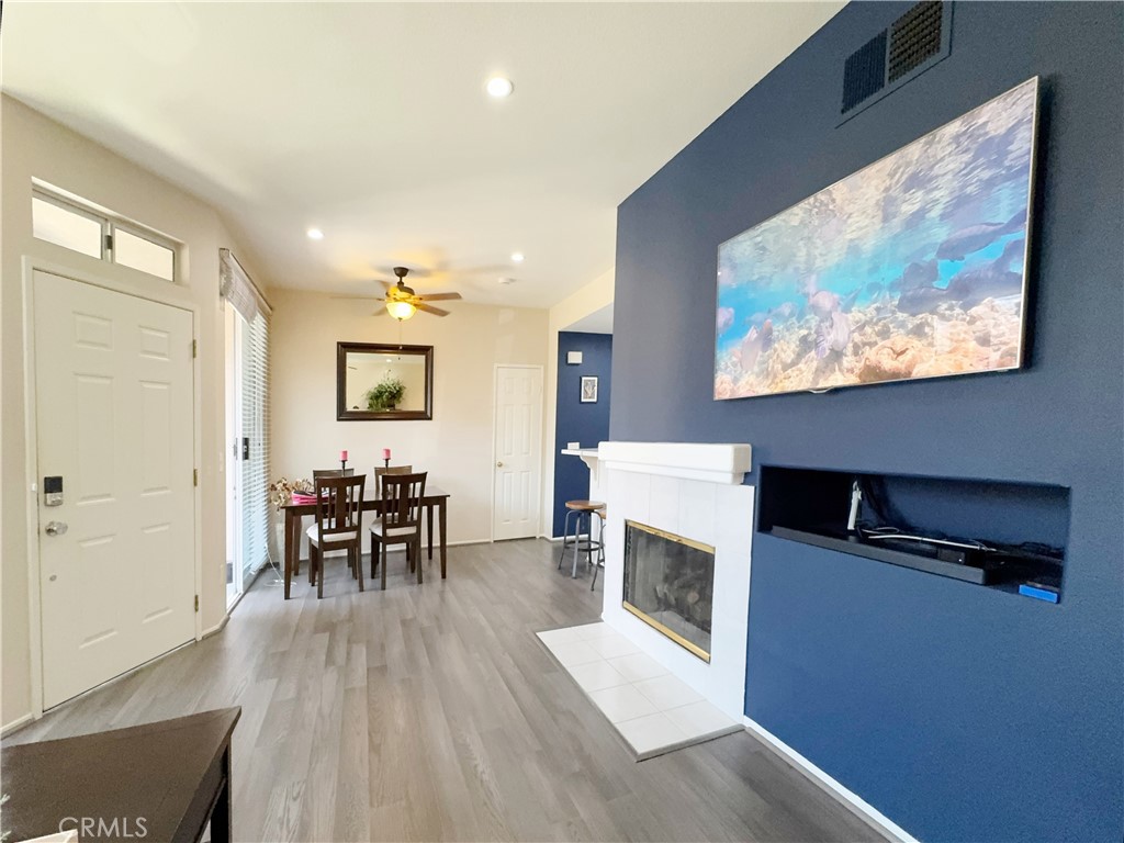 Open and airy living space anchored by a off white tile fireplace and designer navy accent wall with mounted TV. Wood-lo - 29 Waxwing, Aliso Viejo CA 92656 - photo 8