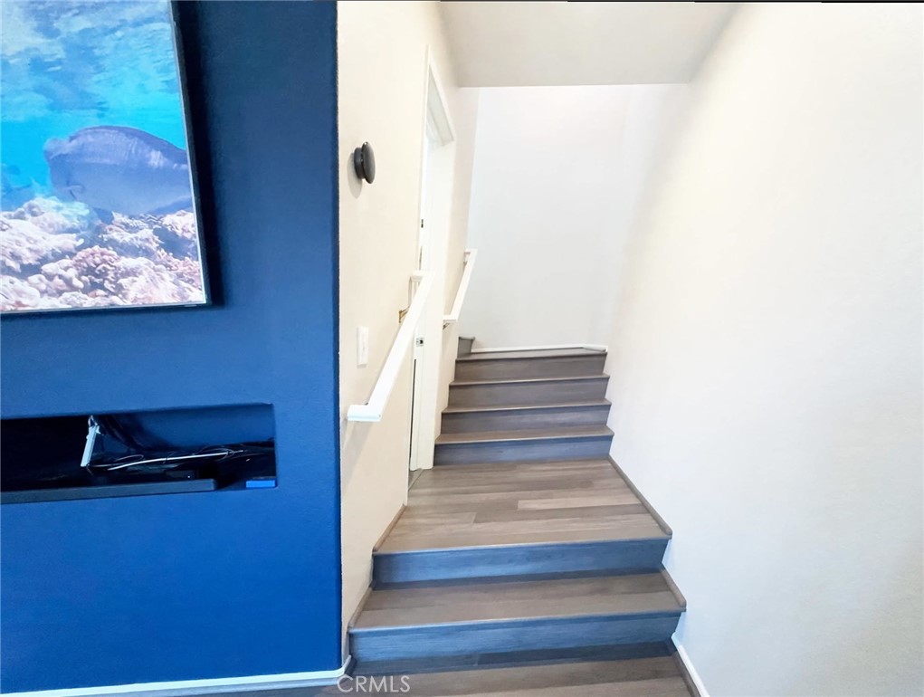 Modern split-level stairway with updated wood-look flooring and bright white railings, flowing from the living area's de - 29 Waxwing, Aliso Viejo CA 92656 - photo 10