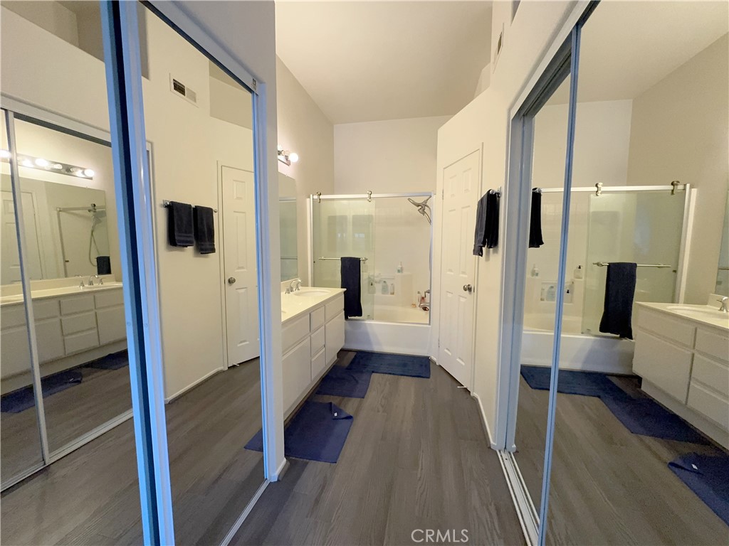 Luxe primary bath viewed through mirrored wardrobes, with long double vanity and glass-enclosed tub/shower. - 29 Waxwing, Aliso Viejo CA 92656 - photo 18