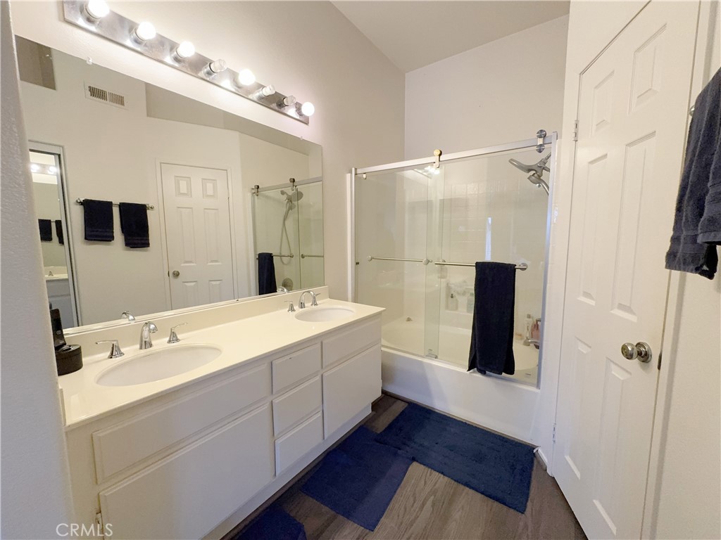 Spa-inspired primary bath with expansive double vanity, oversized mirror, and glass shower over tub. - 29 Waxwing, Aliso Viejo CA 92656 - photo 19