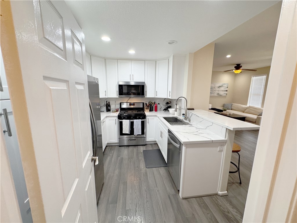 Bright updated kitchen with quartz waterfall bar, stainless gas range, and open flow to living room — move-in ready. - 29 Waxwing, Aliso Viejo CA 92656 - photo 24
