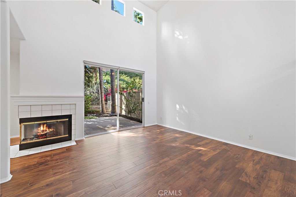 Living room with vaulted ceilings, cozy fireplace, media nook, and view to the private yard. Please note, photo does not - 47 Donatello, Aliso Viejo CA 92656 - photo 11