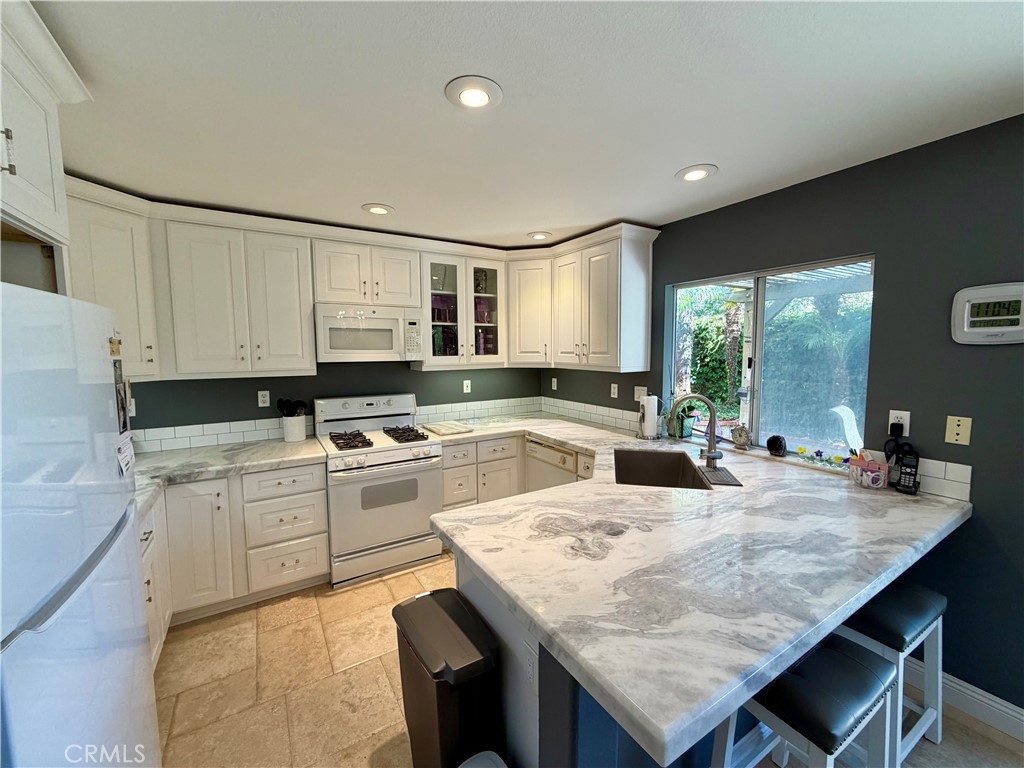 Thick slab stone counters and a peninsula that seats four anchor the kitchen - 6 Mallorn, Aliso Viejo CA 92656 - photo 3