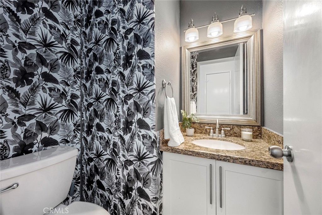 A stylish downstairs powder room adds convenience for guests and features granite countertops, updated cabinetry, and de - 66 Cinnamon Teal, Aliso Viejo CA 92656 - photo 17