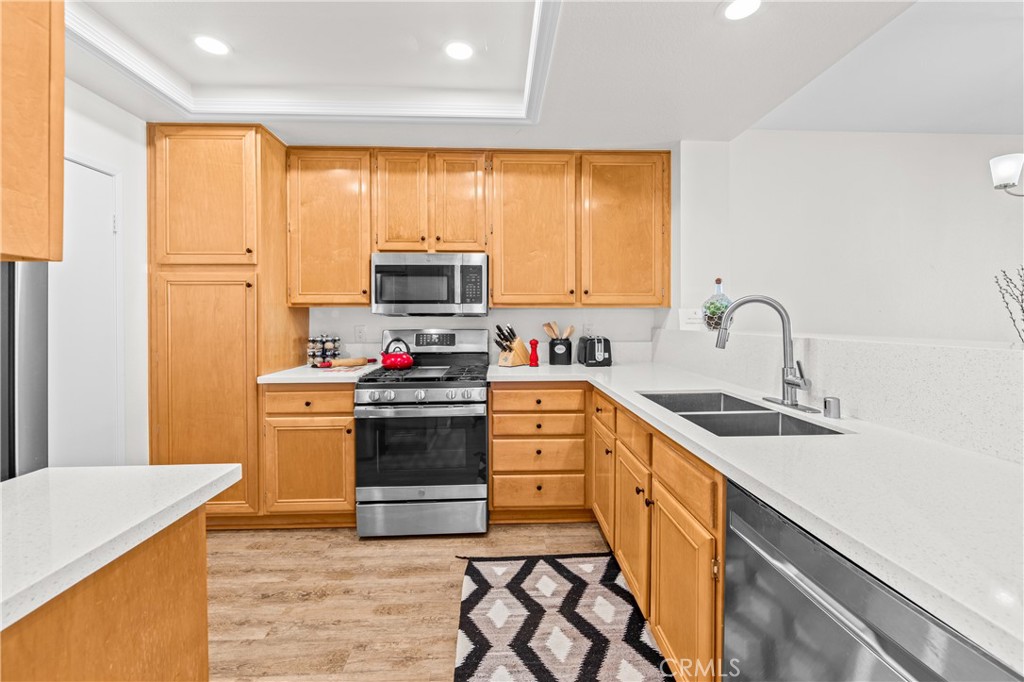 Large kitchen area with quartz counters, stainless appliances and new vinyl flooring. Separate laundry room in the door - 68 Verdin Lane, Aliso Viejo CA 92656 - photo 3