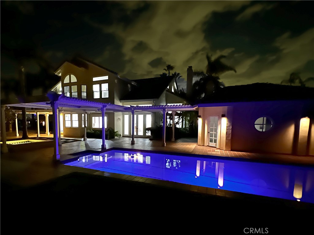 Night view of pool with floating lights. Main house is on the left. Pool/guest home is on the right. - 19 Harbor Pointe, Corona Del Mar CA 92625 - photo 2