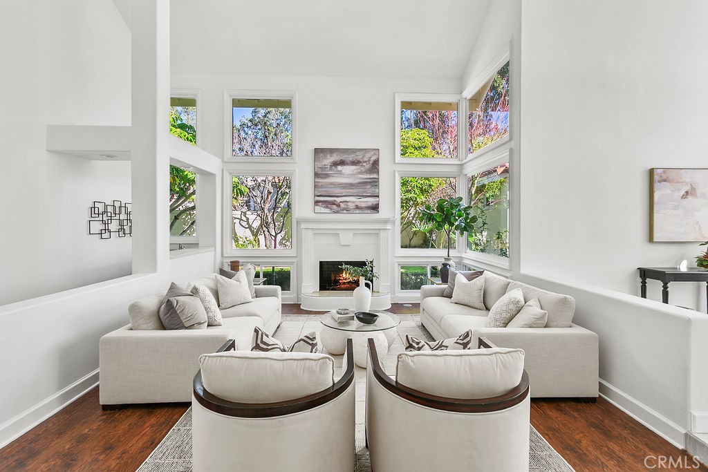 Inviting living room with 2 story ceilings, tall windows, and a zen garden view. Fire in fireplace is virtually created. - 19 Harbor Pointe, Corona Del Mar CA 92625 - photo 9