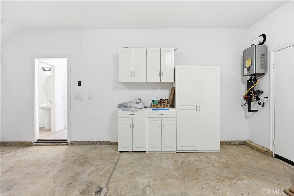 Garage showing tankless water heater and storage cabinets; door to kitchen area - 1044 Palmetto, Costa Mesa CA 92626 - photo 35