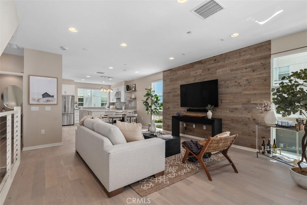 Open-concept living area with custom wood accent wall and seamless flow into the kitchen and dining space - 1529 Greenwich Way, Costa Mesa CA 92627 - photo 1