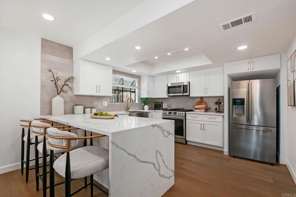 Designer kitchen with quartz countertops, chic white cabinetry, open layout, and eat-in bar top. - 2512 Santa Ana Ave 3, Costa Mesa CA 92627 - photo 1