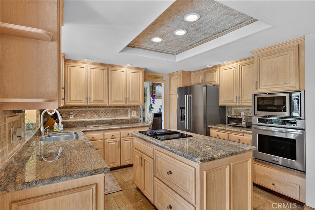 Beautiful wood cabinetry kitchen with granite countertops and mosaic backsplash, island with cooktop, stainless steel si - 2740 Cardinal Drive, Costa Mesa CA 92626 - photo 14