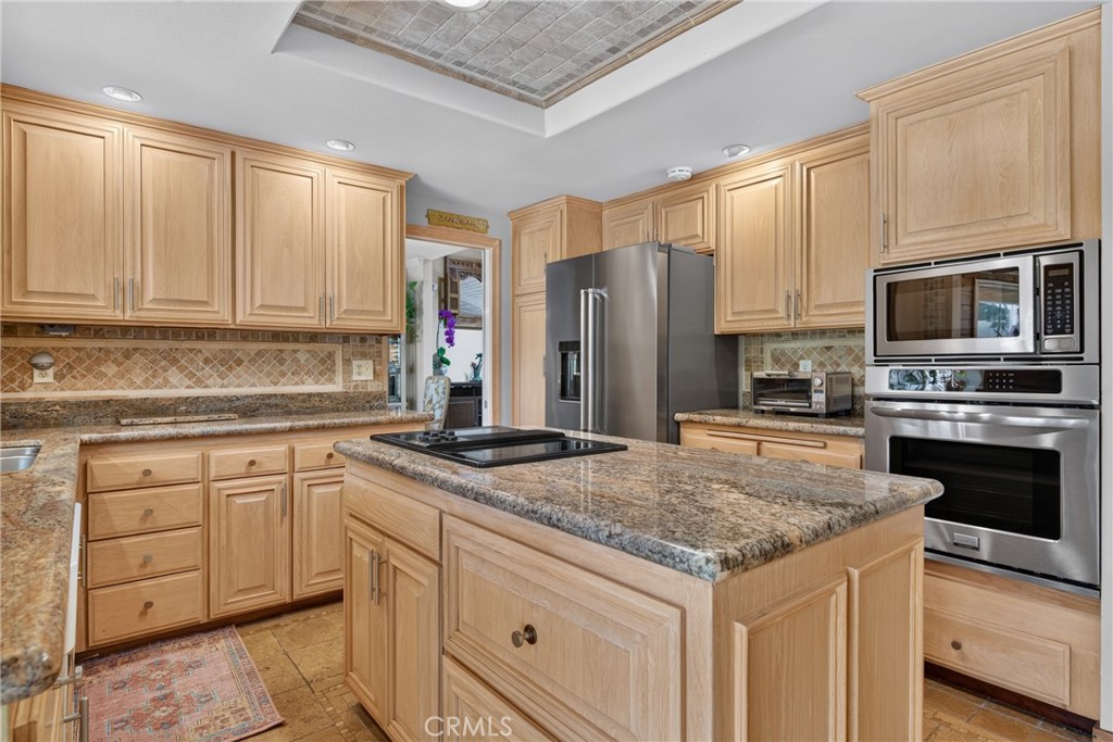Beautiful wood cabinetry kitchen with granite countertops and mosaic backsplash, island with cooktop, stainless steel si - 2740 Cardinal Drive, Costa Mesa CA 92626 - photo 17