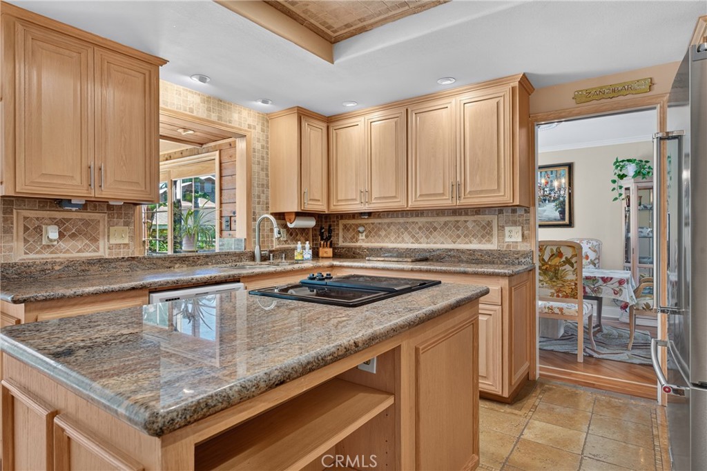 Beautiful wood cabinetry kitchen with granite countertops and mosaic backsplash, island with cooktop, stainless steel si - 2740 Cardinal Drive, Costa Mesa CA 92626 - photo 18