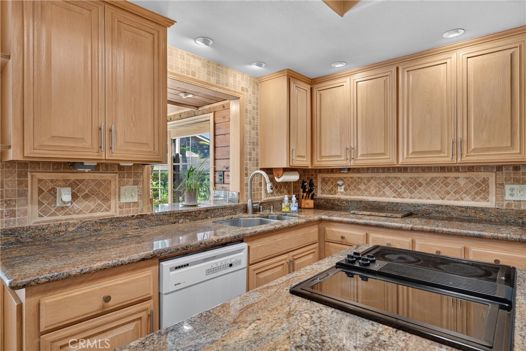 Beautiful wood cabinetry kitchen with granite countertops and mosaic backsplash, island with cooktop, stainless steel si - 2740 Cardinal Drive, Costa Mesa CA 92626 - photo 20