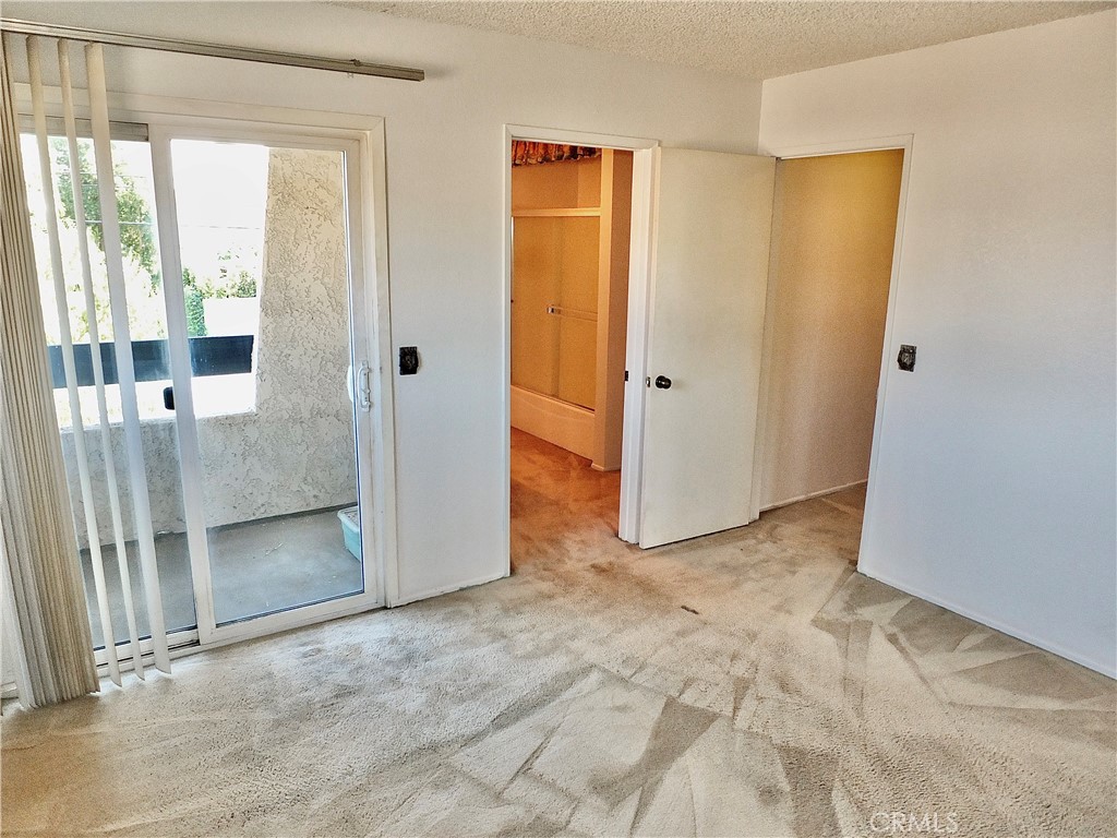 Primary bedroom with sliding door out to the balcony. - 8485 Kington Way 11, Cypress CA 90630 - photo 19