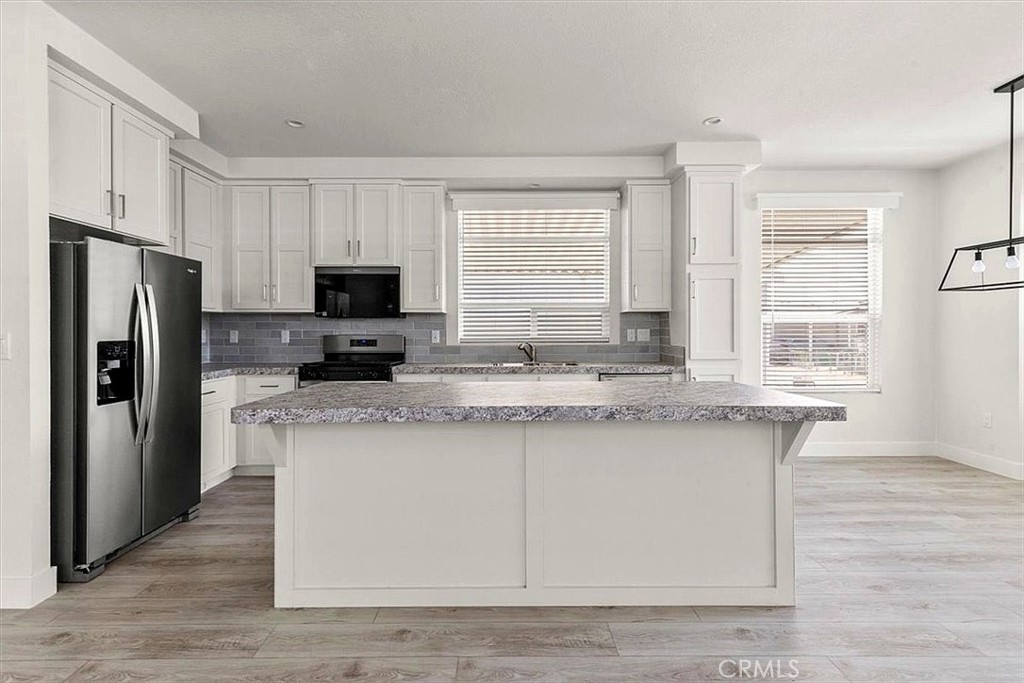 Kitchen: Open island kitchen with white cabinetry, stainless steel appliances, bar seating, recessed lighting, and seaml - 9080 Bloomfield 231, Cypress CA 90630 - photo 7