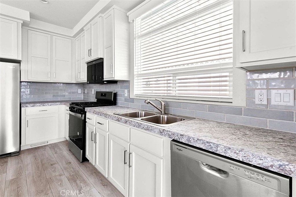 Kitchen: Open island kitchen with white cabinetry, stainless steel appliances, bar seating, recessed lighting, and seaml - 9080 Bloomfield 231, Cypress CA 90630 - photo 9