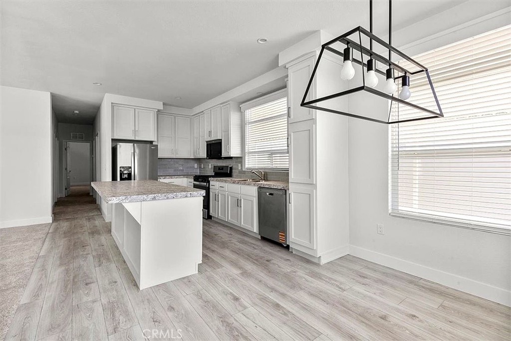 Kitchen: Open island kitchen with white cabinetry, stainless steel appliances, bar seating, recessed lighting, and seaml - 9080 Bloomfield 231, Cypress CA 90630 - photo 10