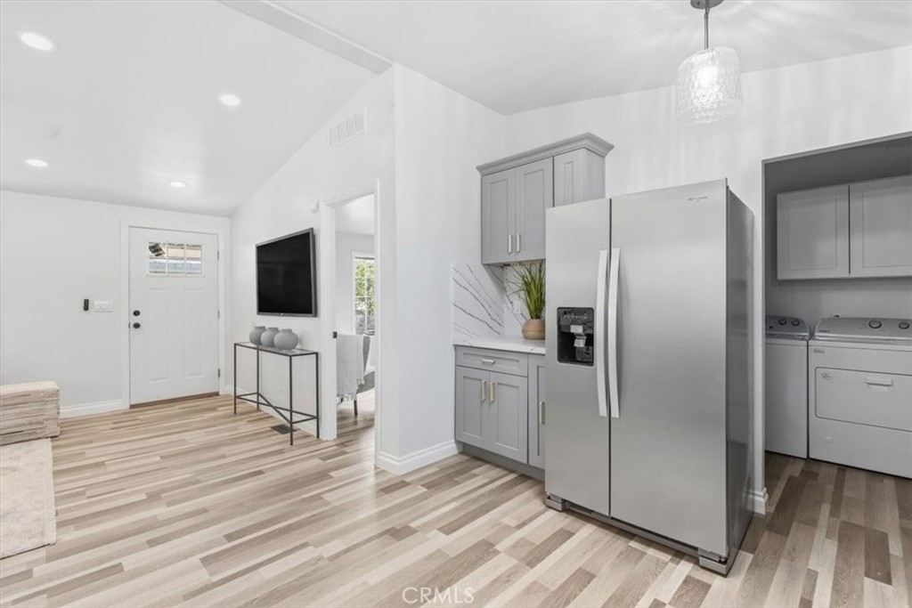 Front door to Kitchen with new stainless refrigerator, flowing to the laundry area and the back door. - 9080 Bloomfield Avenue 153, Cypress CA 90630 - photo 5