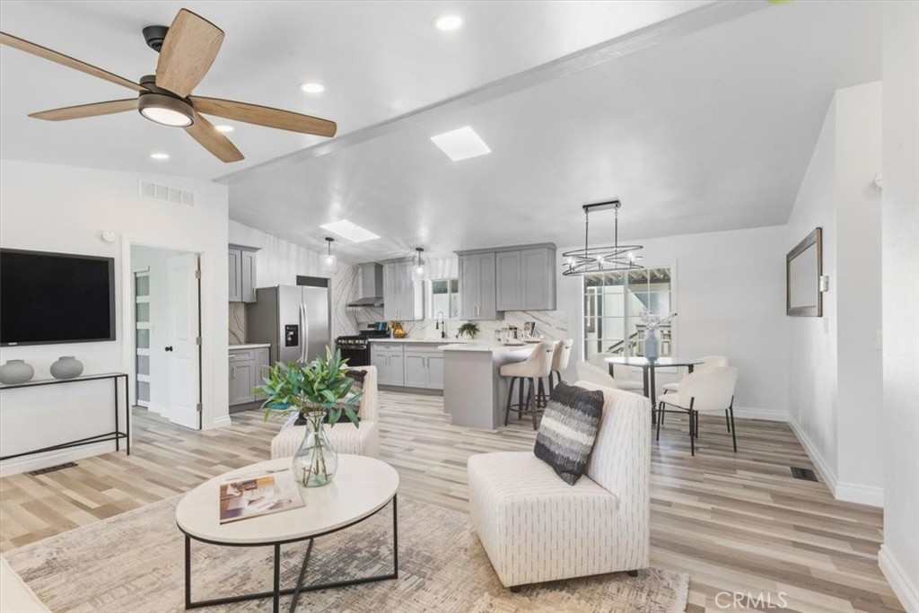 Open-concept living area that flows into the kitchen and dining, with waterproof vinyl plank flooring throughout. - 9080 Bloomfield Avenue 153, Cypress CA 90630 - photo 7