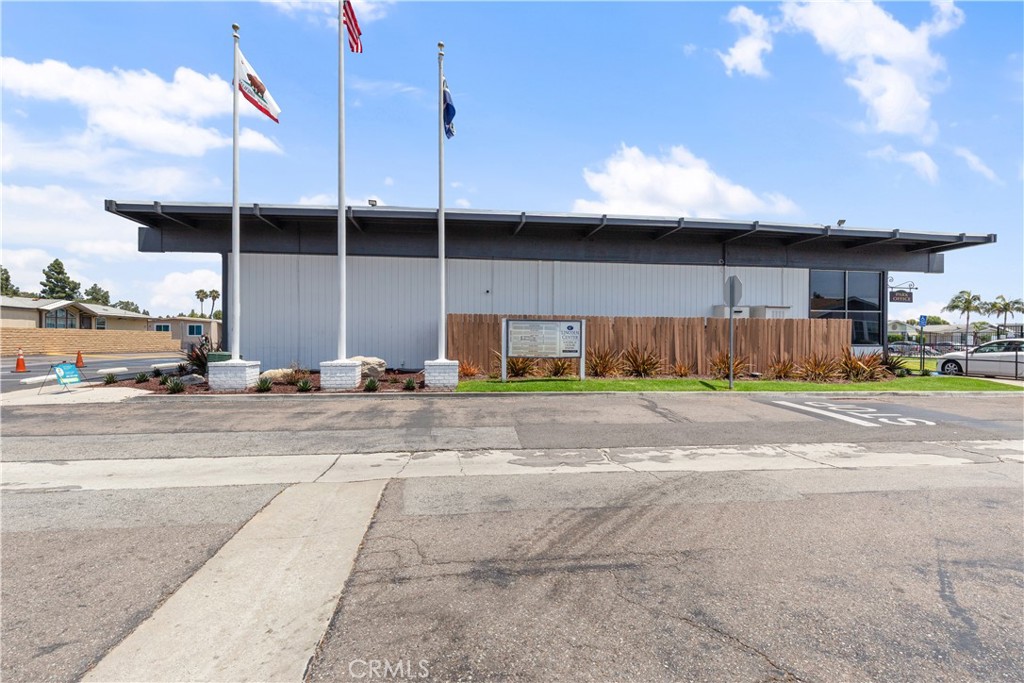 Community clubhouse with landscaped grounds and flagpoles at the entrance. - 9080 Bloomfield Avenue 153, Cypress CA 90630 - photo 20