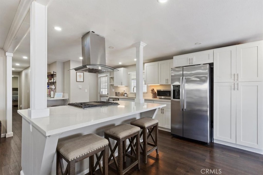 Updated Kitchen: Open island kitchen with white cabinetry, stainless steel appliances, bar seating, recessed lighting, a - 9080 Bloomfield Avenue 293, Cypress CA 90630 - photo 4