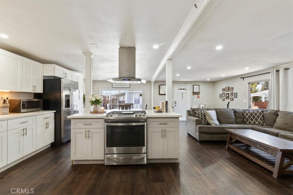 Updated Kitchen: Open island kitchen with white cabinetry, stainless steel appliances, bar seating, recessed lighting, a - 9080 Bloomfield Avenue 293, Cypress CA 90630 - photo 6