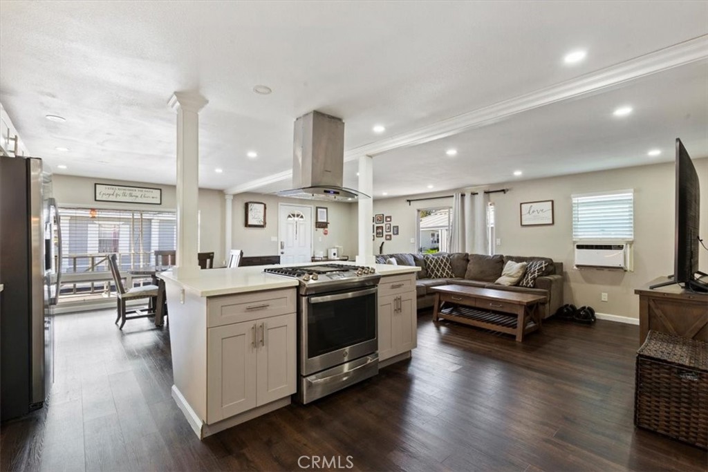 Updated Kitchen: Open island kitchen with white cabinetry, stainless steel appliances, bar seating, recessed lighting, a - 9080 Bloomfield Avenue 293, Cypress CA 90630 - photo 7