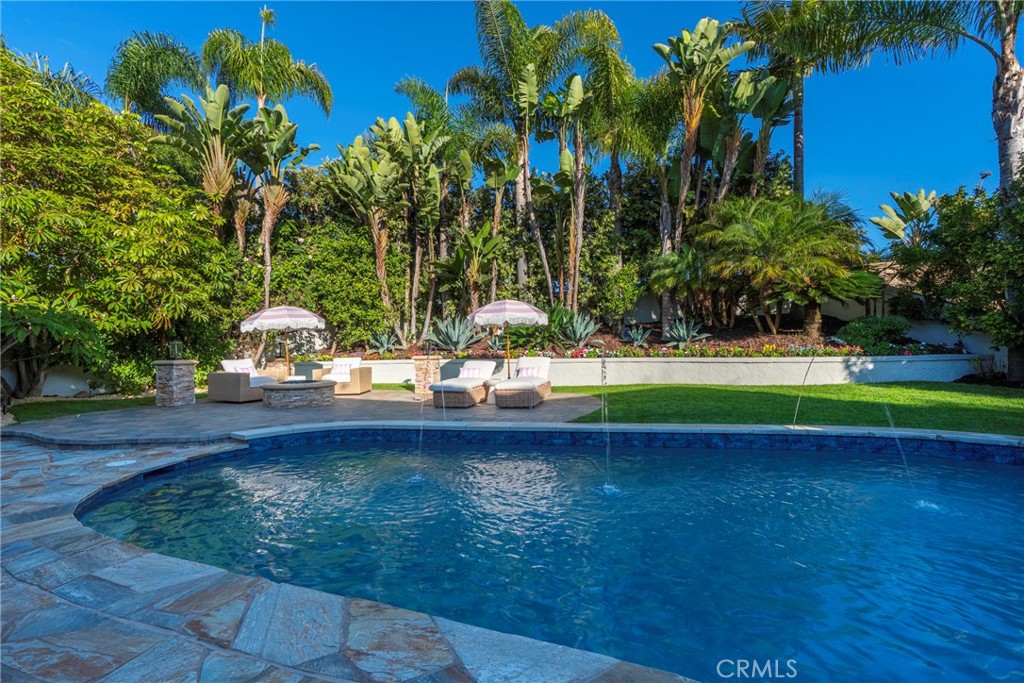 Beautiful backyard oasis featuring a sparkling pool surrounded by lush tropical landscaping and comfortable lounge chair - 20 Regina, Dana Point CA 92629 - photo 1