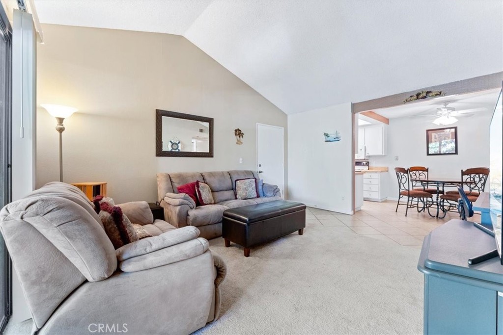 Carpeted living room with vaulted ceiling looks into the dining room. - 25611 Quail Run 32, Dana Point CA 92629 - photo 5