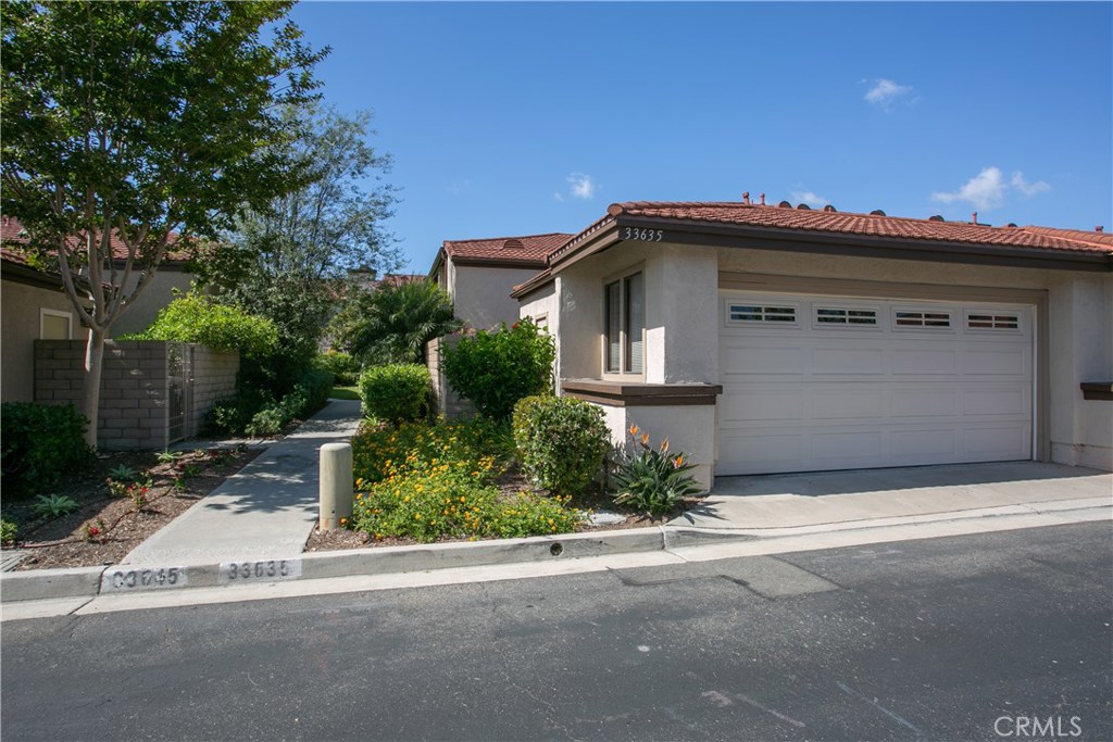 Street view of the house with entrance to private two car garage and pathway to front door. - 33635 Tidewater Drive 74, Dana Point CA 92629 - photo 1
