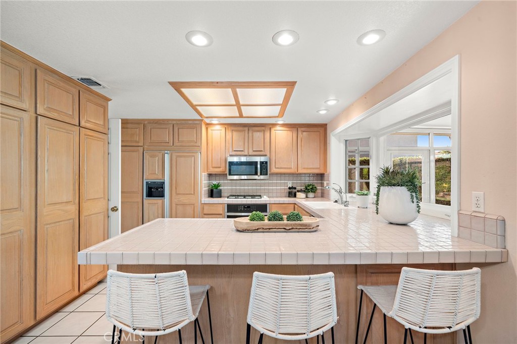 Spacious kitchen with an abundance of cabinetry, a bay window, and bar seating - 9115 McBride River Avenue, Fountain Valley CA 92708 - photo 19