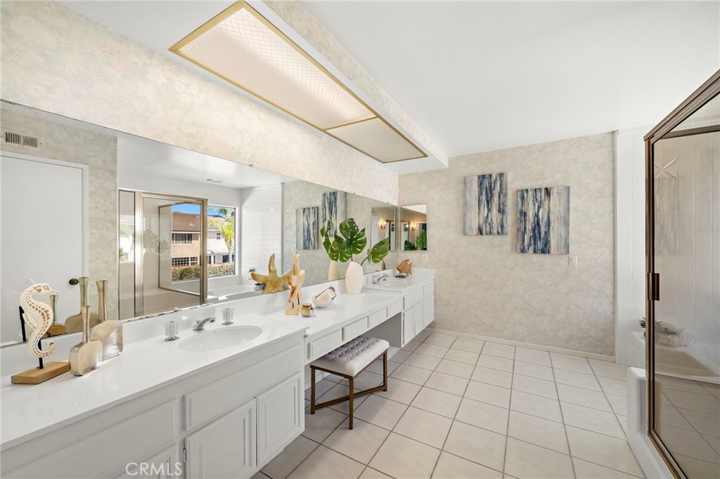 Primary spa-inspired bathroom with dual sinks, sit down vanity, oval soaking tub, separate shower, privacy toilet, and 2 - 9115 McBride River Avenue, Fountain Valley CA 92708 - photo 31