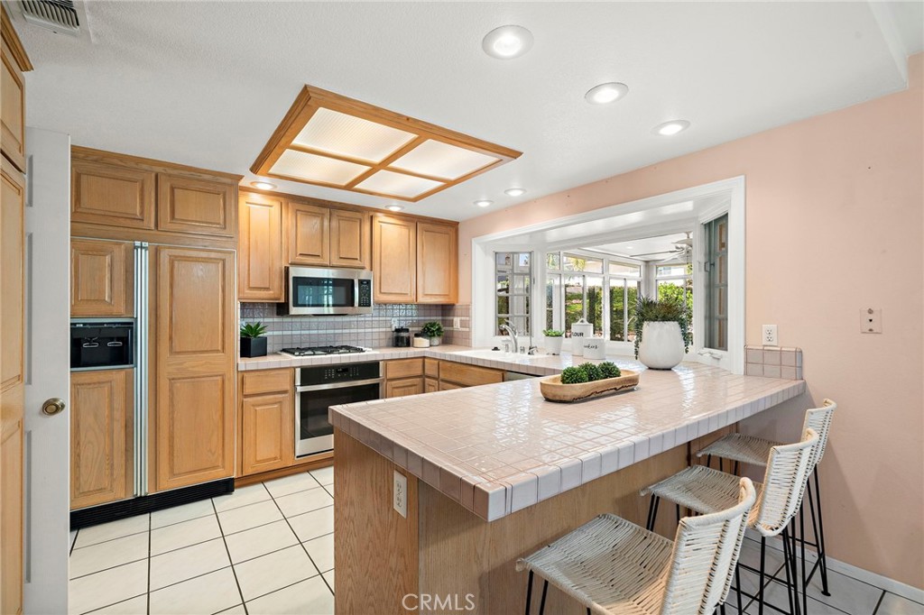 Kitchen with abundant wood cabinetry and convenient breakfast-bar seating. - 9115 McBride River Avenue, Fountain Valley CA 92708 - photo 18