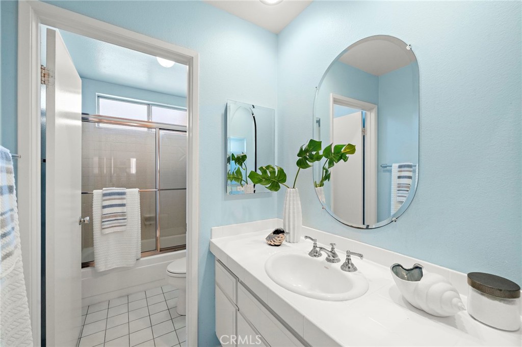 Bright bathroom with a long vanity and glass-enclosed tub and shower. - 9115 McBride River Avenue, Fountain Valley CA 92708 - photo 35