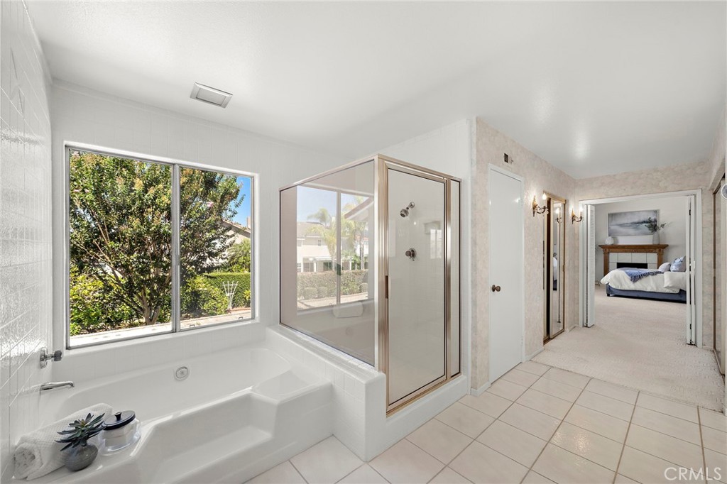 Bathroom with a soaking tub beneath a garden-view window and a separate shower. - 9115 McBride River Avenue, Fountain Valley CA 92708 - photo 40