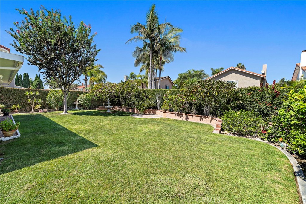 Spacious green lawn framed by mature trees and landscaped borders. - 9115 McBride River Avenue, Fountain Valley CA 92708 - photo 43