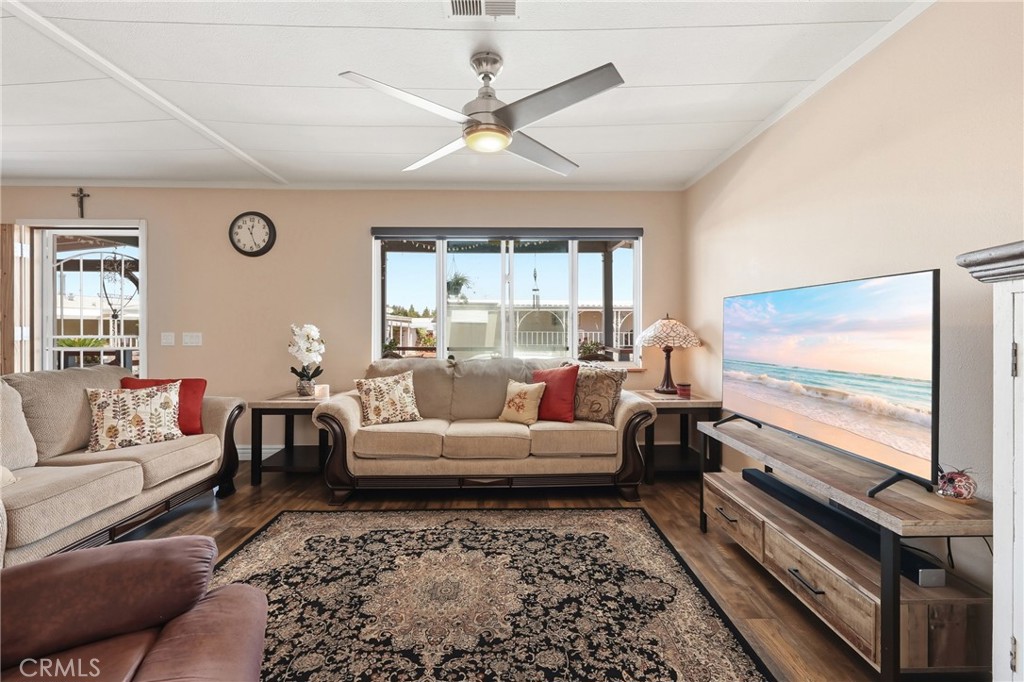 The living room is filled with ample natural light and features dual-pane windows, a ceiling fan, and beautiful laminate - 1201 W Valencia Drive 13, Fullerton CA 92833 - photo 2
