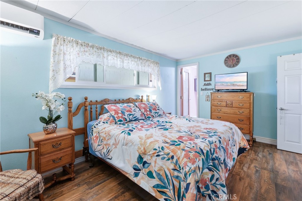 The spacious primary bedroom features a private ensuite full bathroom and a wall-mounted A/C and heating unit, providing - 1201 W Valencia Drive 13, Fullerton CA 92833 - photo 4
