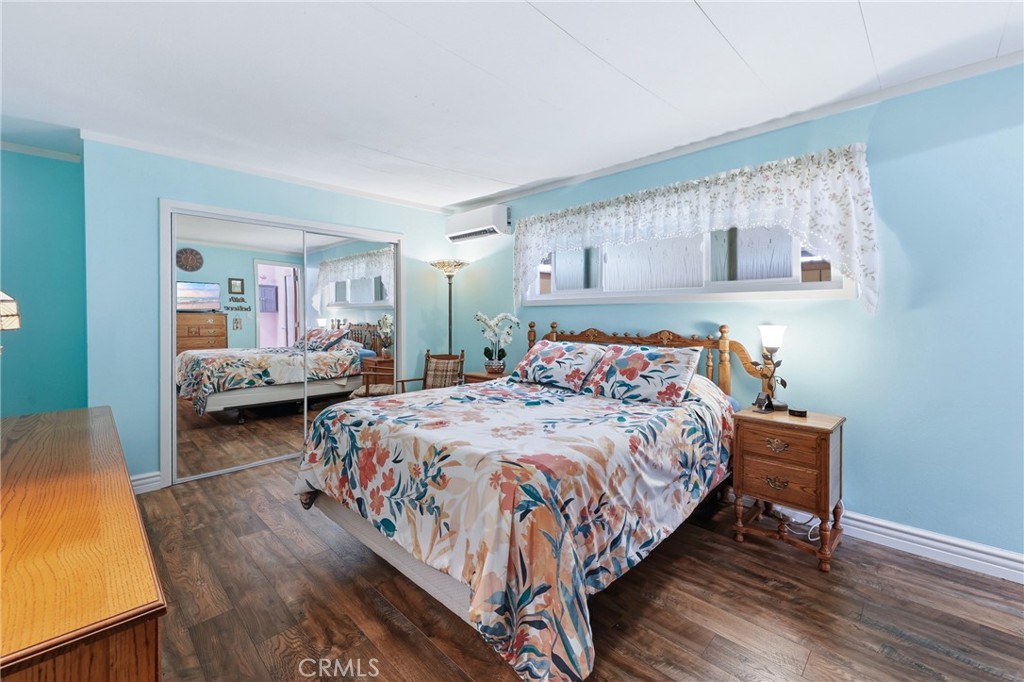 Primary bedroom with mirrored closets and stunning laminate flooring. - 1201 W Valencia Drive 13, Fullerton CA 92833 - photo 22