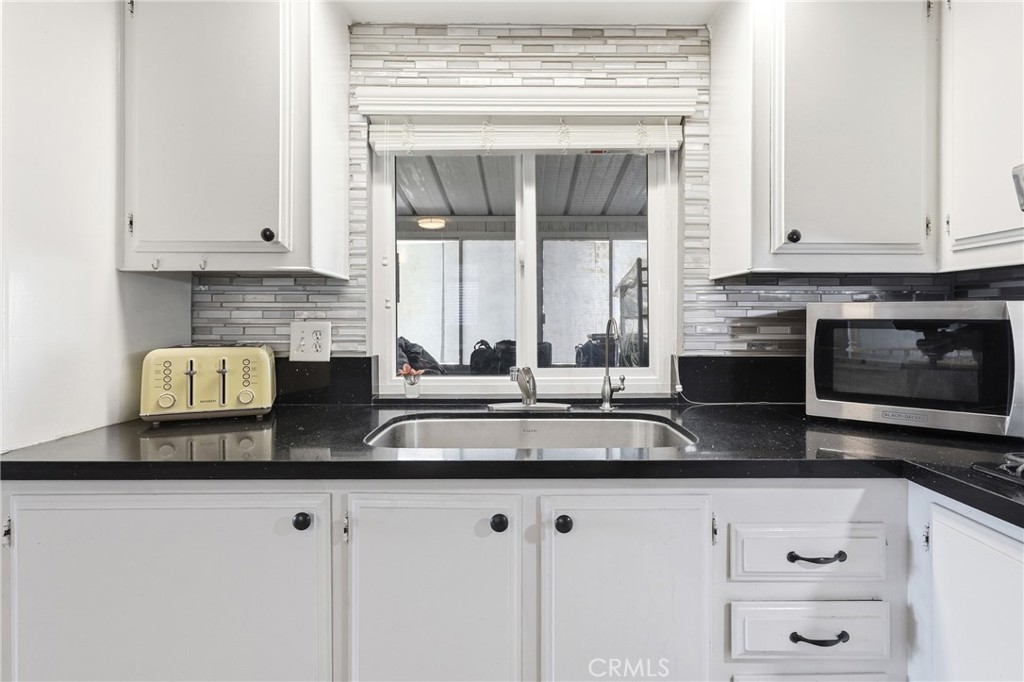 The kitchen features sleek black Quartz countertops and crisp white cabinetry. - 1201 W Valencia Drive 69, Fullerton CA 92833 - photo 6