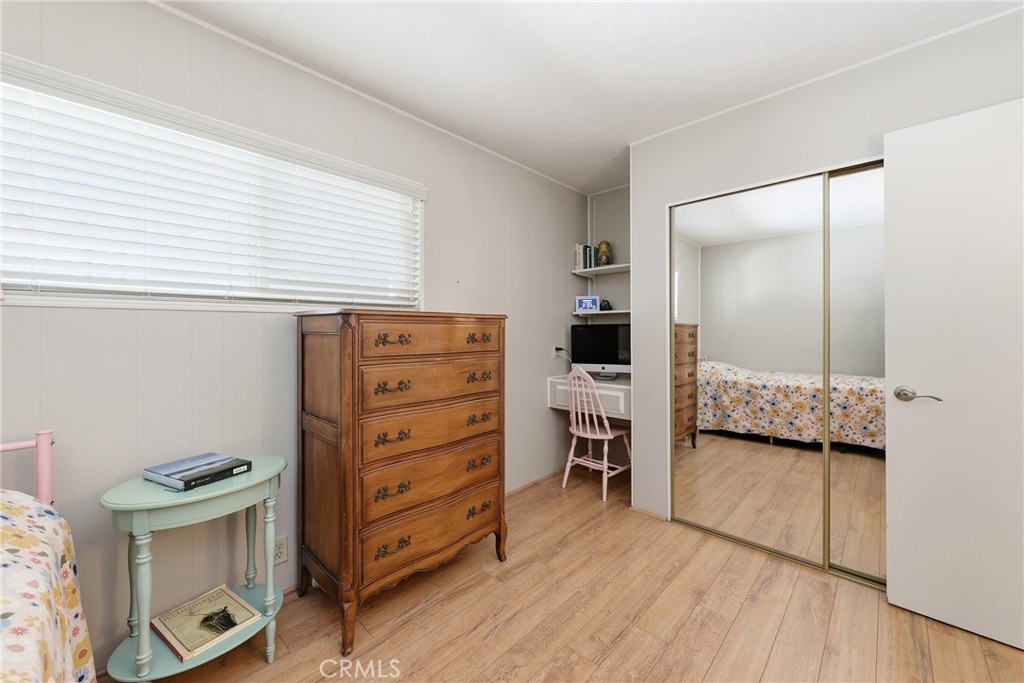 The guest bedroom features mirrored closet doors and a convenient built-in office area. - 1201 W Valencia Drive 69, Fullerton CA 92833 - photo 13