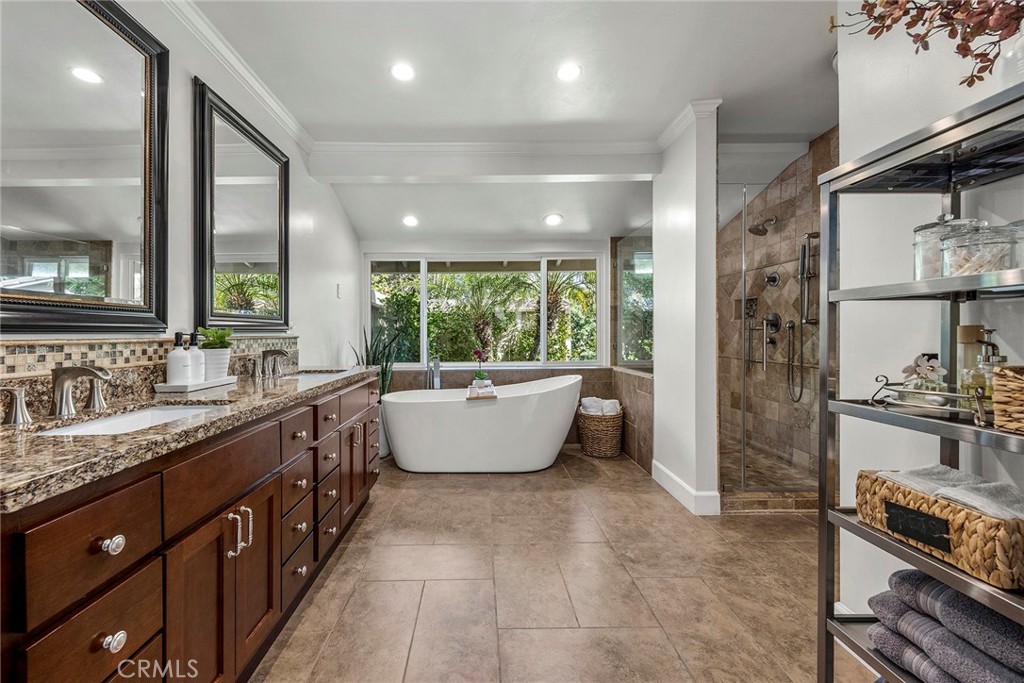 Spa-inspired primary bath features a freestanding soaking tub, dual-sink vanity and a large picture window framing lush - 2100 Yucca Avenue, Fullerton CA 92835 - photo 30