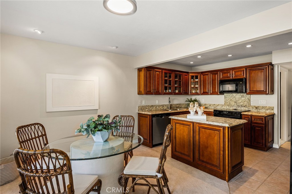 The kitchen and dining area blend warmth and function, featuring rich wood cabinetry and a center island. - 12632 Romaine Wy, Garden Grove CA 92845 - photo 13