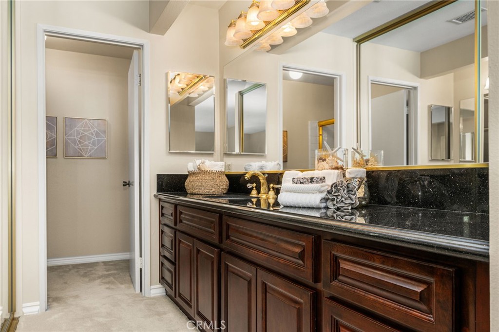 Primary dressing area features mirrored closet doors and a long vanity with abundant cabinet storage. - 12632 Romaine Wy, Garden Grove CA 92845 - photo 34