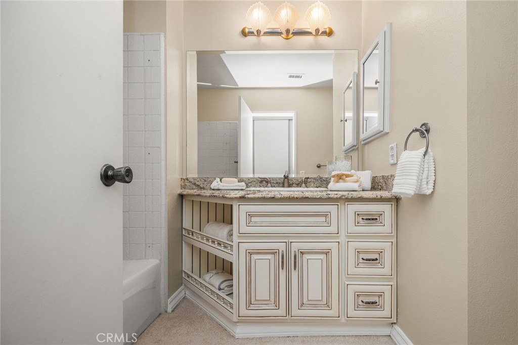 Stylish powder room featuring a granite-topped wood vanity and decorative glass-front wall cabinet. - 12632 Romaine Wy, Garden Grove CA 92845 - photo 39
