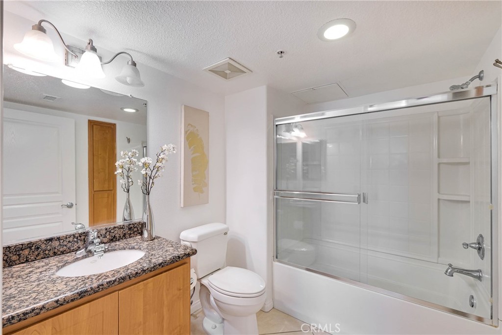 Spacious hallway bathroom features shower over tub with glass sliding door enclosure - 12664 Chapman Avenue 1402, Garden Grove CA 92840 - photo 12
