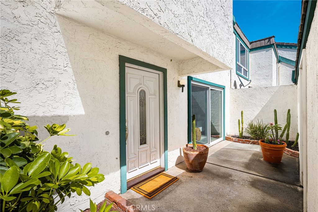 Front entry Welcoming courtyard entry featuring a decorative glass front door and charming greenery. - 6931 Danvers Dr, Garden Grove CA 92845 - photo 3