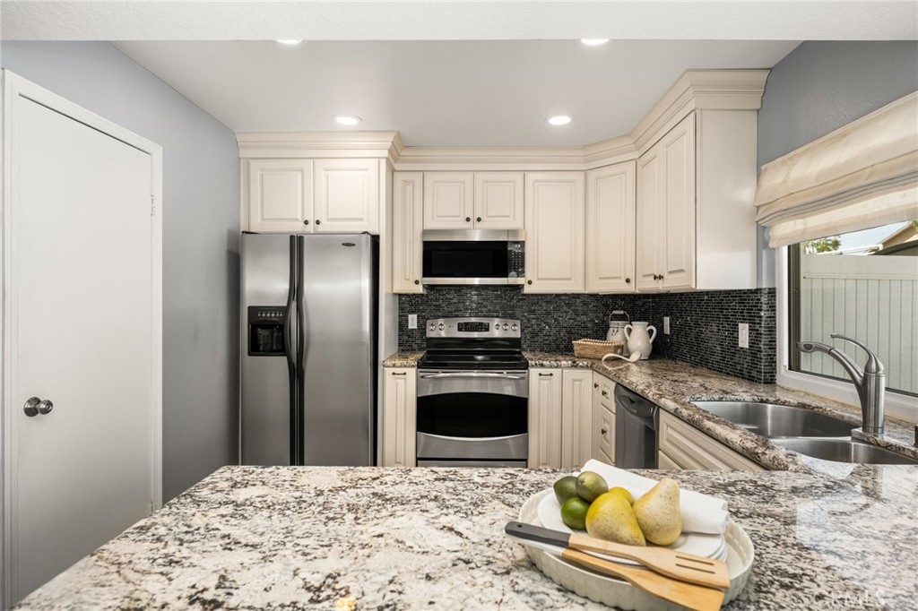 Beautiful kitchen featuring granite countertops, a center island, white cabinetry, and stainless steel appliance - 6931 Danvers Dr, Garden Grove CA 92845 - photo 17